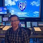 录音艺术毕业生Ryan Kennedy坐在一个大的录音控制台前.